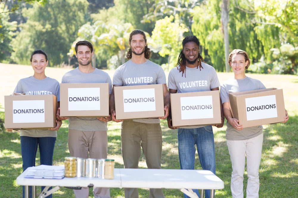 Happy volunteers with donation boxes in park on a sunny day Happy volunteers with donation boxes in park on a sunny day